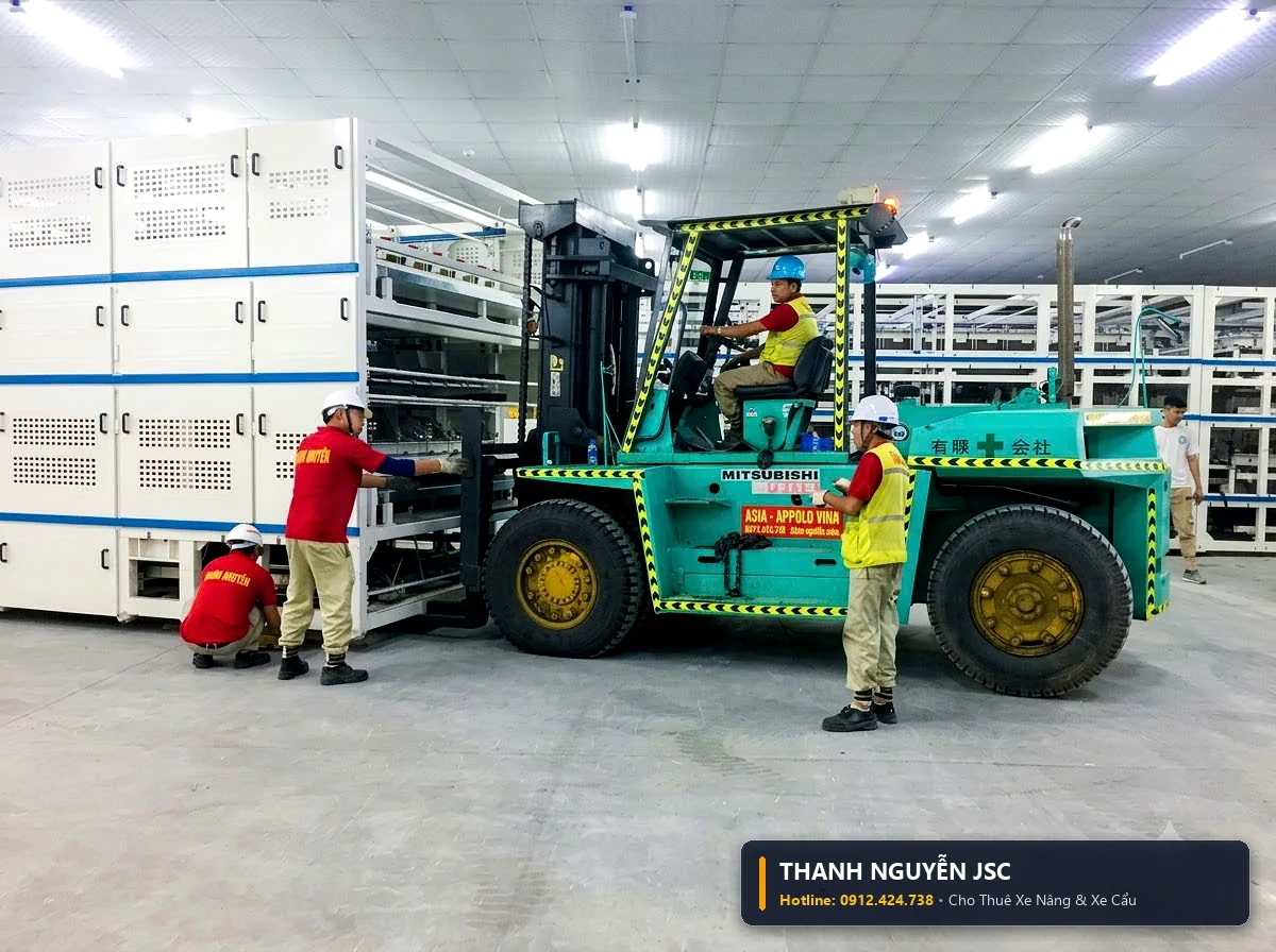 Xe nâng hàng đưa khối máy móc công nghiệp áp sát dây chuyền tự động hóa với sự điều phối của công nhân THÀNH HUY HOÀNG tại Quảng Ninh